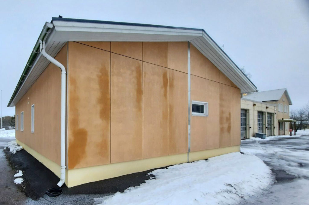 Pieni, suorakaiteen muotoinen rakennus lumisessa maisemassa, taustalla toinen samankaltainen rakennus.